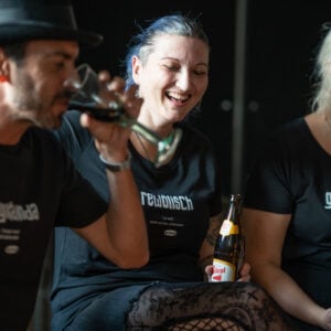 Ein Mann und zwei Frauen machen Party und tragen dabei OstSeele-Shirts.
