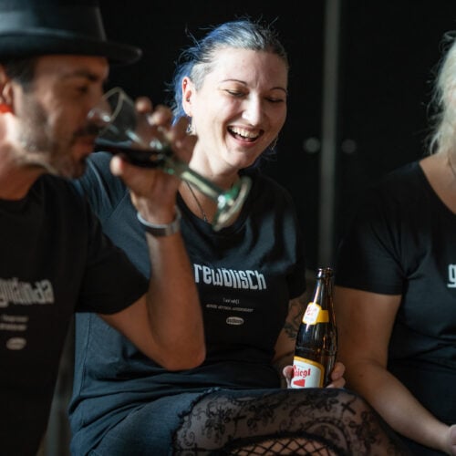 Ein Mann und zwei Frauen machen Party und tragen dabei OstSeele-Shirts.