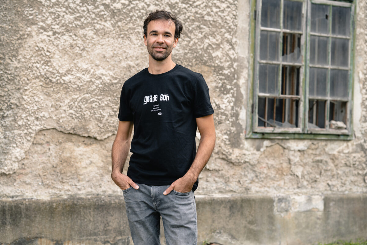 Junger Mann mit OstSeele-Shirt vor einer Fabriksmauer