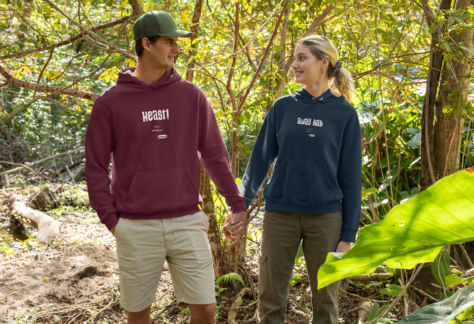Eine Frau und ein Mann in OstSeele-Hoodies spazieren durch den Wald.